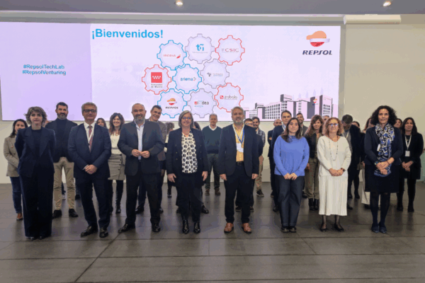 Foto de grupo que muestra a los representantes de las empresas mencionadas de pie. En el fondo de la imagen sale proyectada una diapositiva con los logos de las empresas participantes en el proyecto Madrid Vuela Sostenible